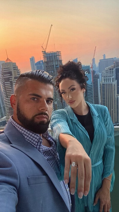 beautiful engaged couple sharing her engagement ring on top of a skyscraper